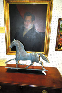 A copper running horse weathervane stands in front of an 1820s portrait in the Ponzi's Antiques booth.